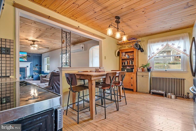 dining area with radiator, a fireplace, a wall mounted AC, ceiling fan, and wooden ceiling