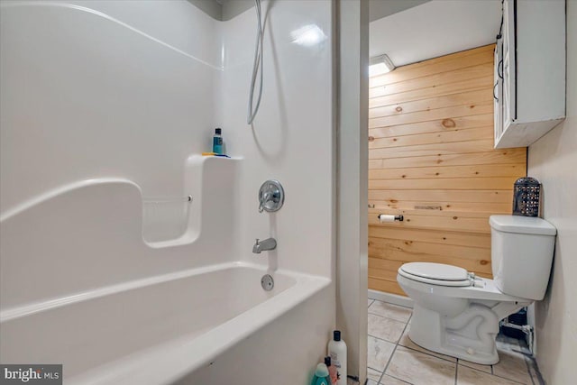 bathroom with wooden walls, toilet, tub / shower combination, and tile patterned flooring