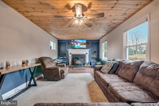 living room featuring ceiling fan, vaulted ceiling, a wood stove, and wooden ceiling