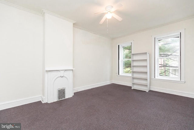 unfurnished living room with dark colored carpet, ornamental molding, and ceiling fan