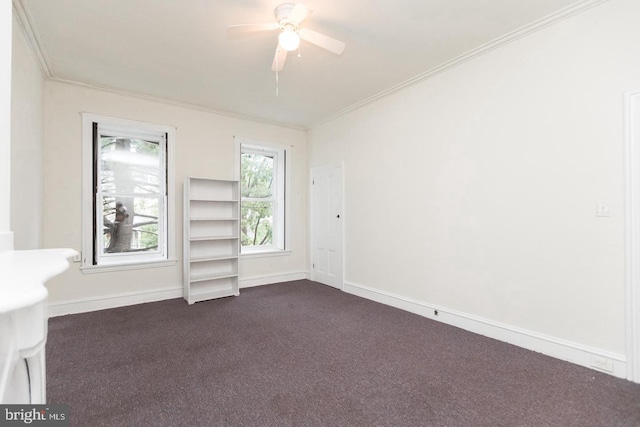 empty room featuring dark colored carpet, ornamental molding, and ceiling fan