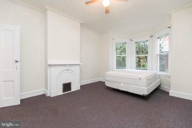 unfurnished bedroom featuring ornamental molding, dark carpet, and ceiling fan