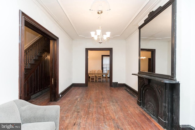 hallway featuring ornamental molding, dark hardwood / wood-style floors, and an inviting chandelier