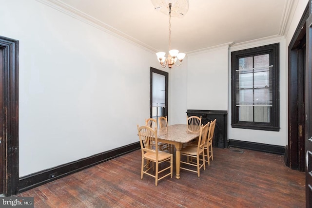 dining room featuring dark wood-type flooring, ornamental molding, and an inviting chandelier