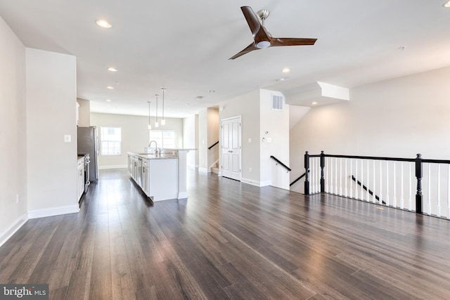 unfurnished living room featuring sink, dark wood-type flooring, and ceiling fan