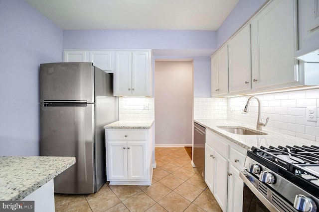 kitchen with stainless steel appliances, light stone countertops, sink, and white cabinets