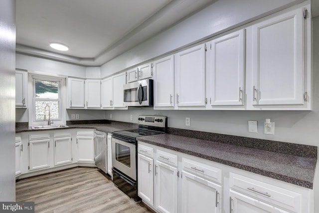 kitchen featuring white cabinetry, appliances with stainless steel finishes, sink, and light hardwood / wood-style flooring