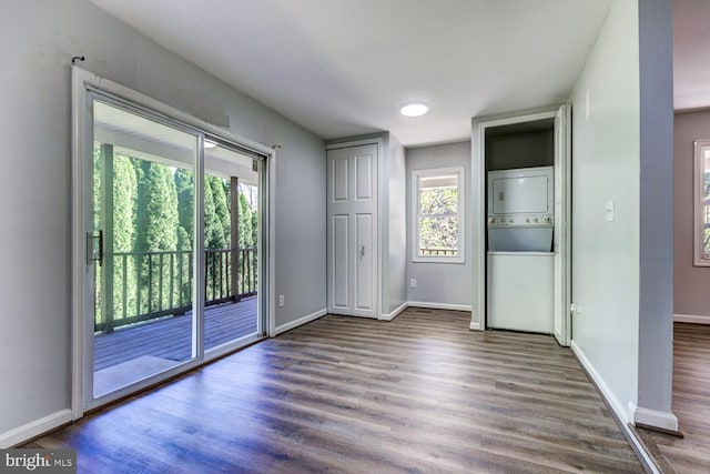 interior space with multiple windows, stacked washing maching and dryer, wood-type flooring, and access to exterior