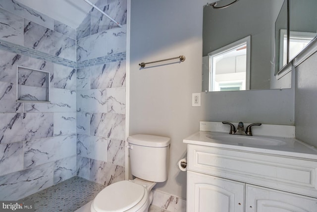 bathroom with vanity, tiled shower, and toilet