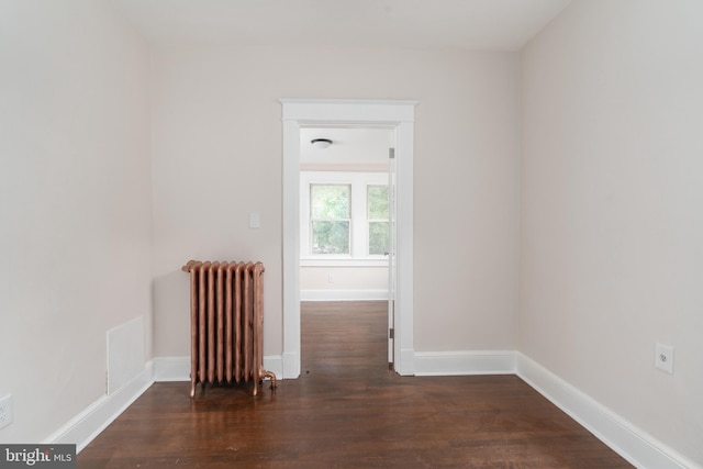 spare room featuring dark hardwood / wood-style floors and radiator