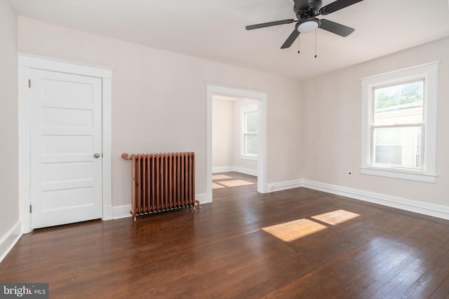 unfurnished room with ceiling fan, radiator heating unit, and dark hardwood / wood-style flooring