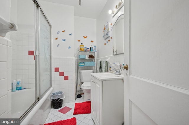 full bathroom featuring toilet, tile walls, vanity, enclosed tub / shower combo, and tile patterned flooring