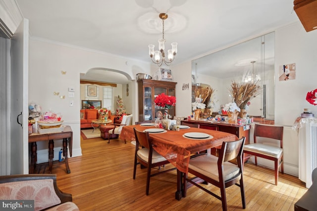 dining space with ornamental molding, a chandelier, and light wood-type flooring