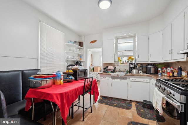 kitchen featuring appliances with stainless steel finishes, white cabinetry, tasteful backsplash, extractor fan, and light tile patterned flooring