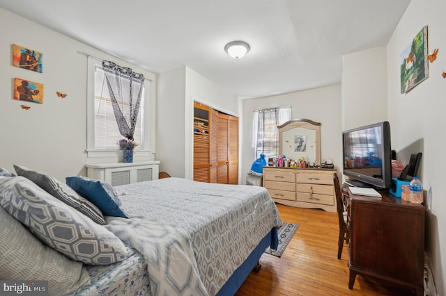 bedroom with wood-type flooring, a closet, and radiator heating unit