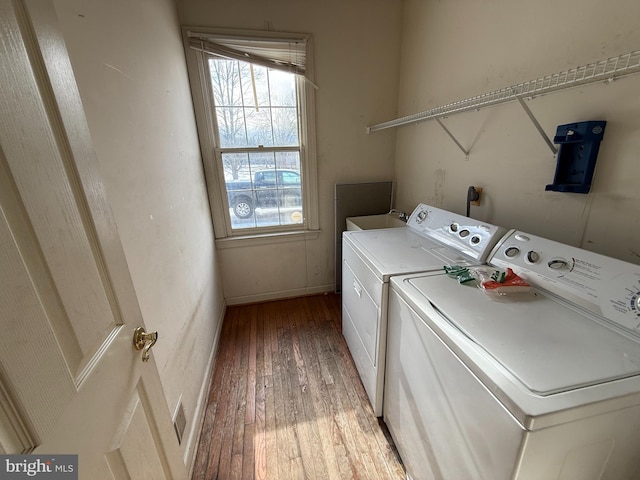 clothes washing area with wood-type flooring and washing machine and dryer