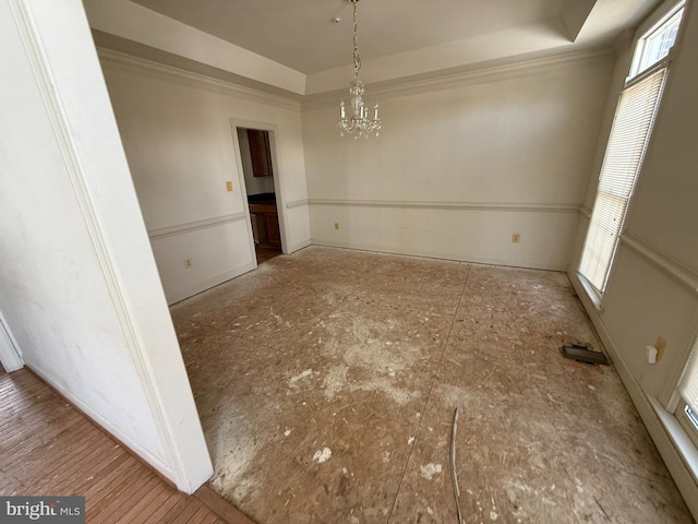 unfurnished dining area with an inviting chandelier and a tray ceiling