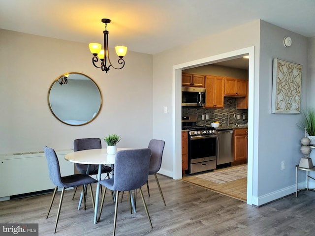 dining space featuring baseboards, an inviting chandelier, and light wood-style flooring