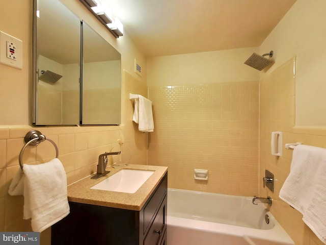 full bath with visible vents, vanity, tile walls, and shower / bathtub combination