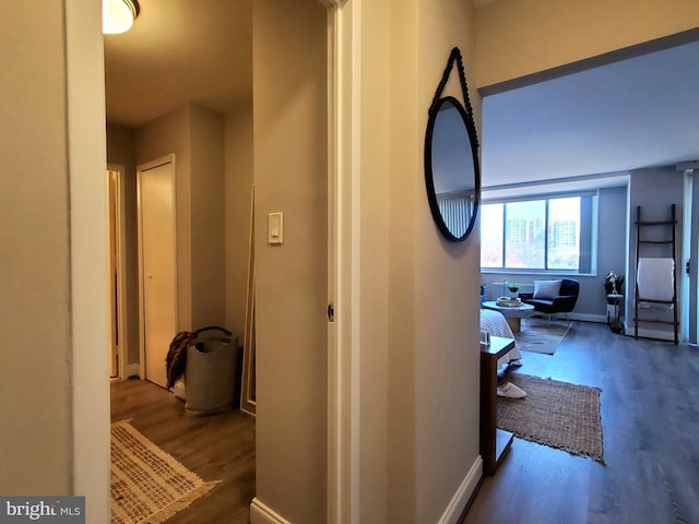 corridor with baseboards and wood finished floors