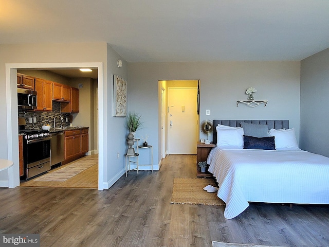 bedroom featuring wood finished floors, baseboards, and a sink