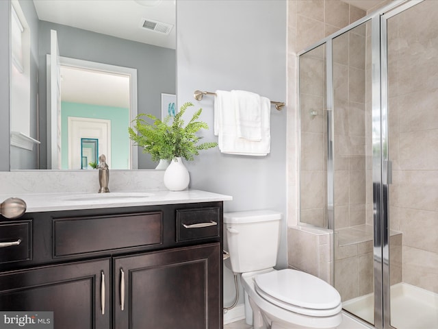 bathroom featuring vanity, a shower with shower door, and toilet