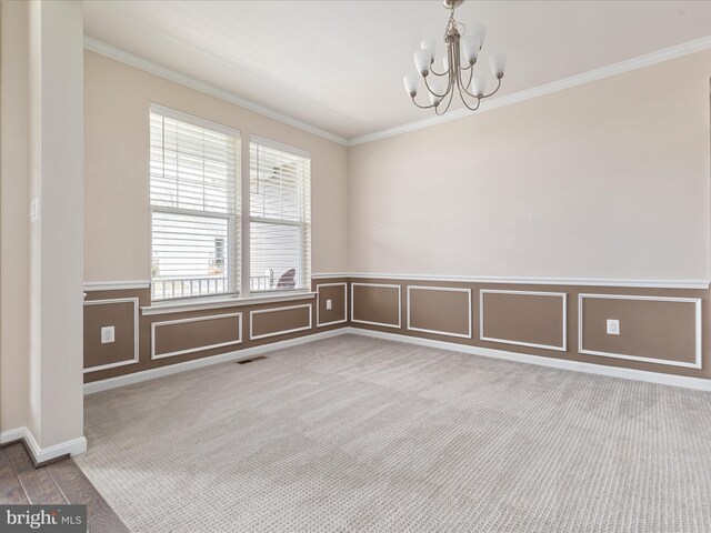 spare room featuring ornamental molding, carpet floors, and a notable chandelier
