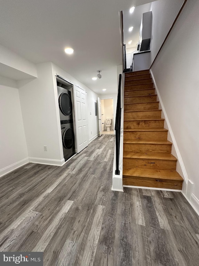 stairs featuring wood-type flooring and stacked washing maching and dryer