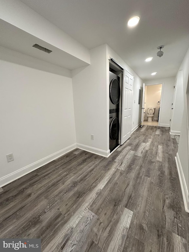 laundry room featuring dark hardwood / wood-style flooring and stacked washing maching and dryer