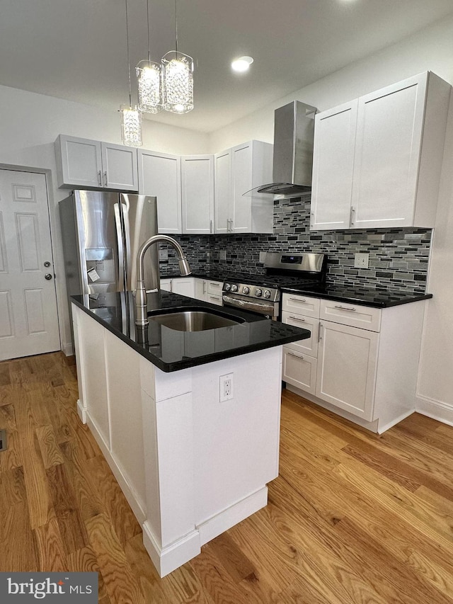 kitchen with white cabinetry, wall chimney range hood, stainless steel appliances, and an island with sink