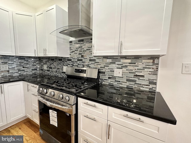 kitchen featuring white cabinetry, stainless steel gas range oven, exhaust hood, and decorative backsplash