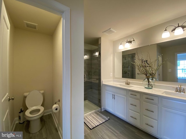 bathroom with vanity, hardwood / wood-style floors, a shower with shower door, and toilet