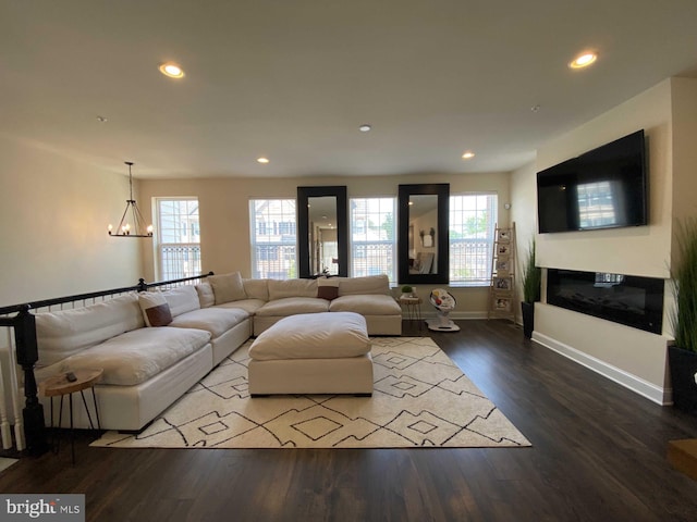 living room with a healthy amount of sunlight, wood-type flooring, and a notable chandelier