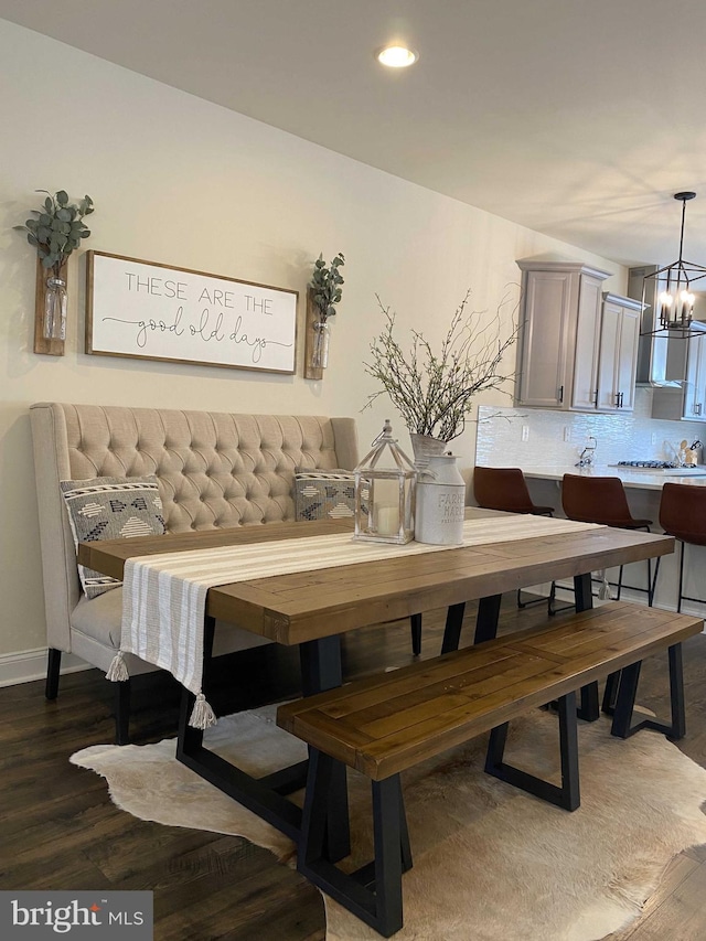 dining space with dark wood-type flooring and a chandelier