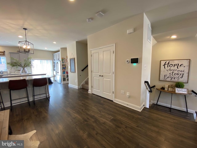 interior space with an inviting chandelier, a kitchen bar, dark hardwood / wood-style floors, and hanging light fixtures