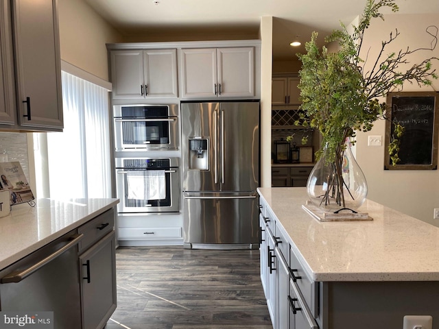 kitchen featuring appliances with stainless steel finishes, light stone countertops, decorative backsplash, and gray cabinetry