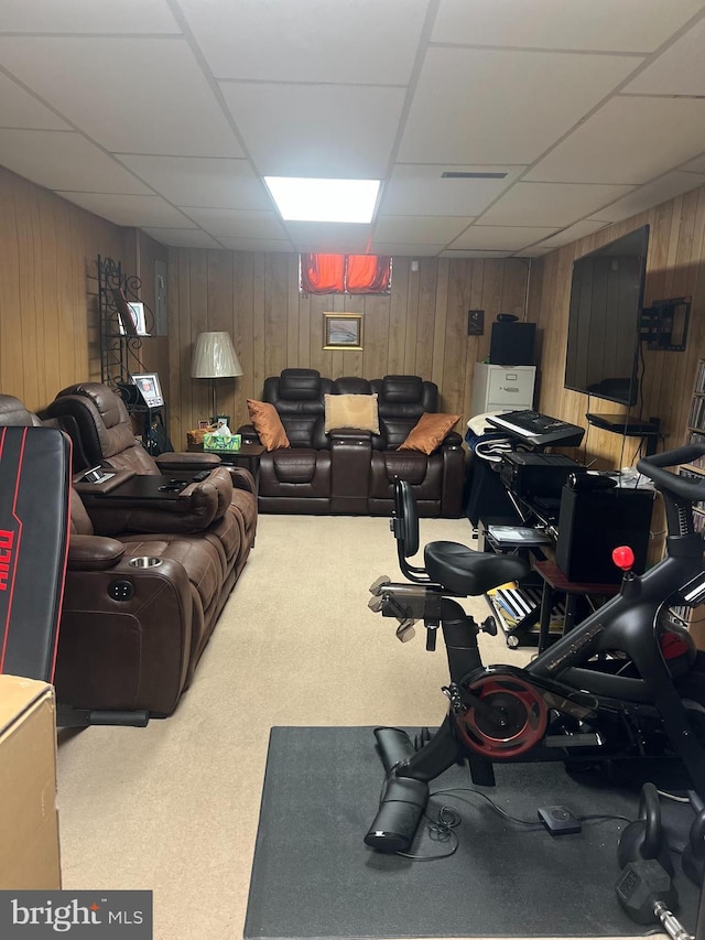 workout room with a drop ceiling, wooden walls, and carpet