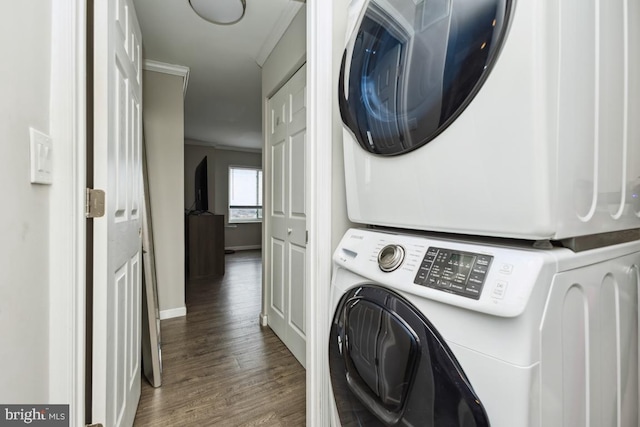 laundry area with stacked washing maching and dryer, dark wood-type flooring, and crown molding