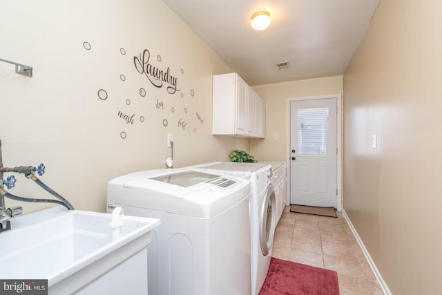 clothes washing area featuring washing machine and dryer, cabinets, sink, and light tile patterned floors