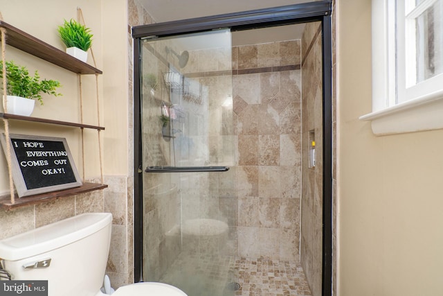 bathroom with tile walls, toilet, and a shower with door