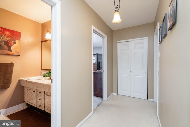 hall with sink and light carpet