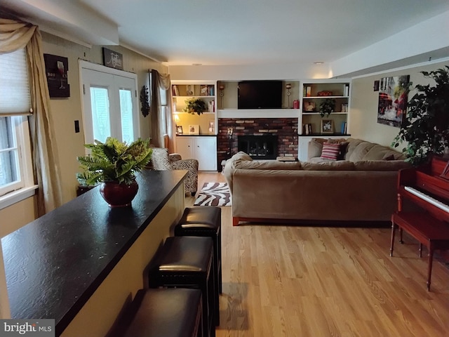 living room featuring a wealth of natural light, a brick fireplace, and light hardwood / wood-style flooring