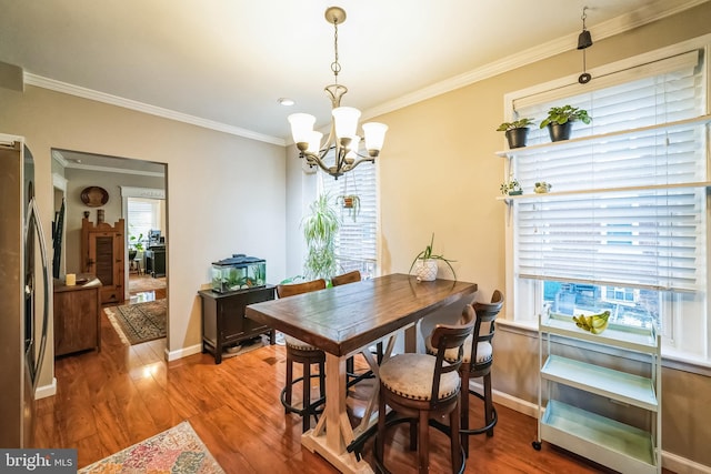 dining area featuring crown molding, hardwood / wood-style flooring, and an inviting chandelier