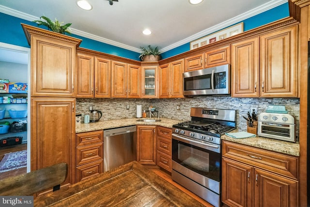 kitchen with light stone countertops, appliances with stainless steel finishes, ornamental molding, and decorative backsplash