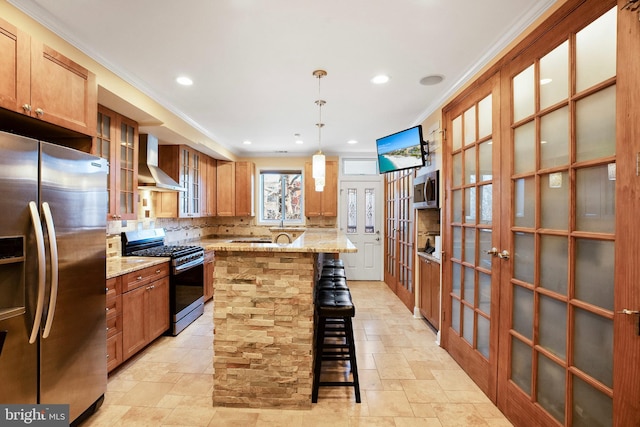 kitchen with french doors, wall chimney exhaust hood, appliances with stainless steel finishes, a kitchen breakfast bar, and a kitchen island