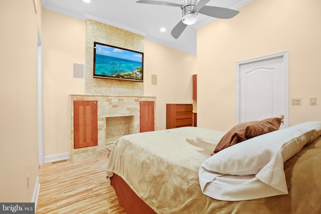 bedroom featuring ornamental molding, ceiling fan, and a fireplace