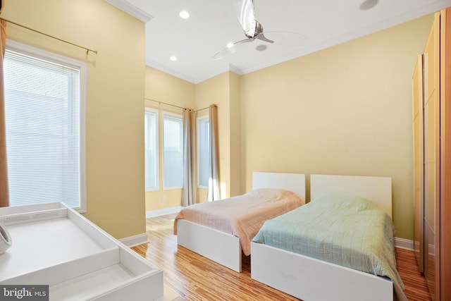 bedroom with multiple windows, ornamental molding, ceiling fan, and light hardwood / wood-style floors