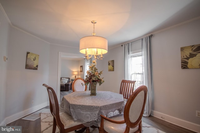 dining space with crown molding, wood-type flooring, and an inviting chandelier