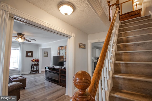 stairway with hardwood / wood-style floors, a textured ceiling, and ceiling fan