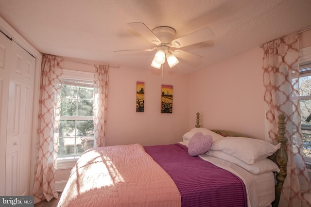 bedroom featuring multiple windows, a textured ceiling, ceiling fan, and a closet